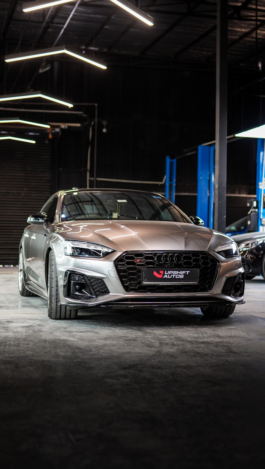 Close view of the silver Audi S5's honeycomb grille, S badge and headlamp.