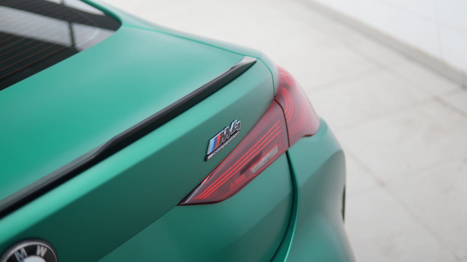Close view of the M4 badge and tail lamp on the satin green boot lid.