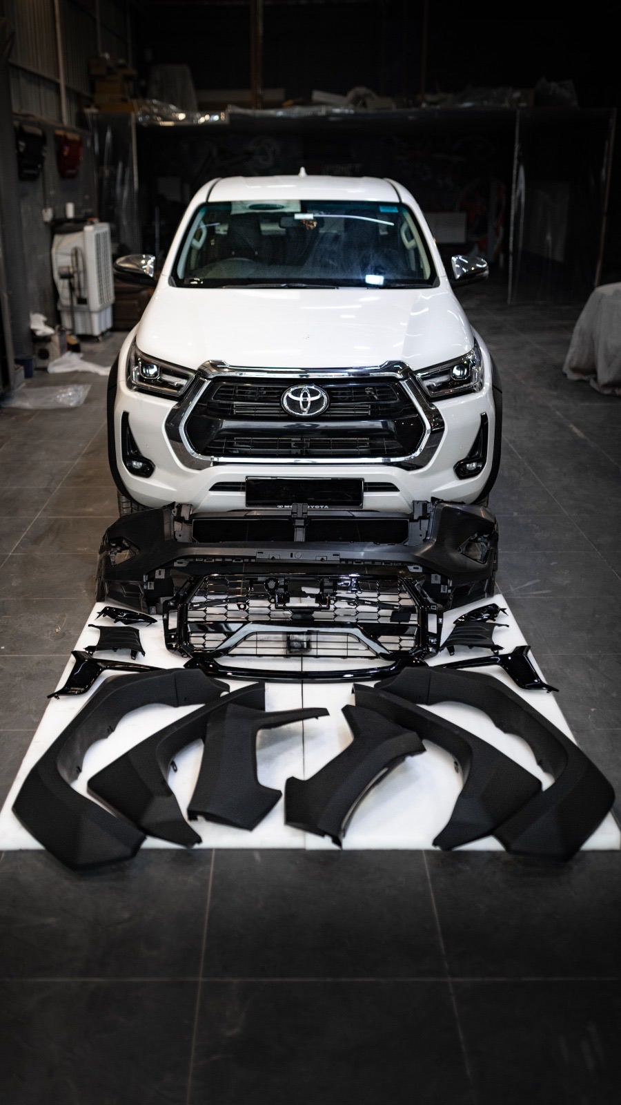 Toyota Hilux with its body kit laid out in front of it