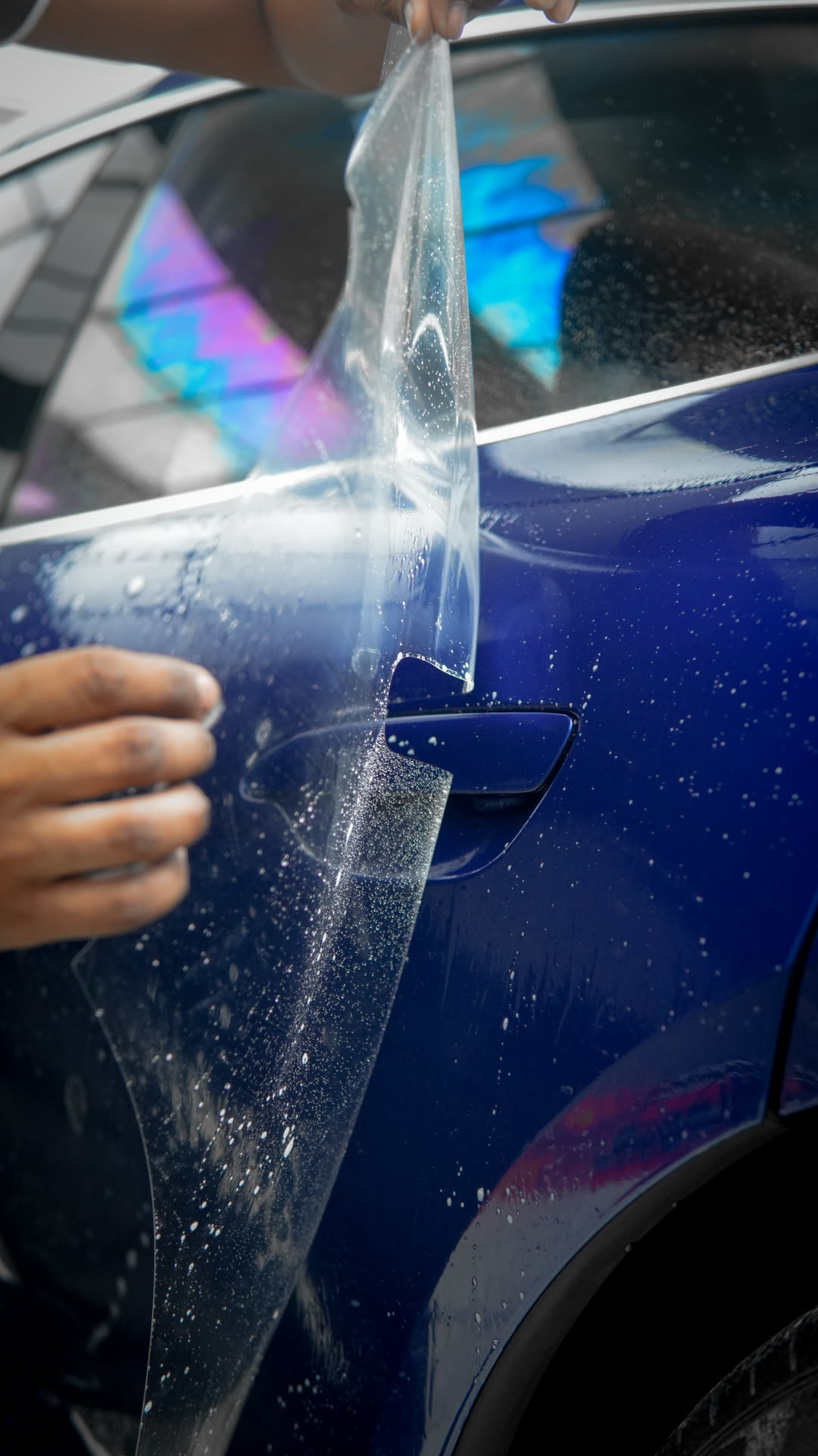 Clear film being laid over the Taycan's rear quarter